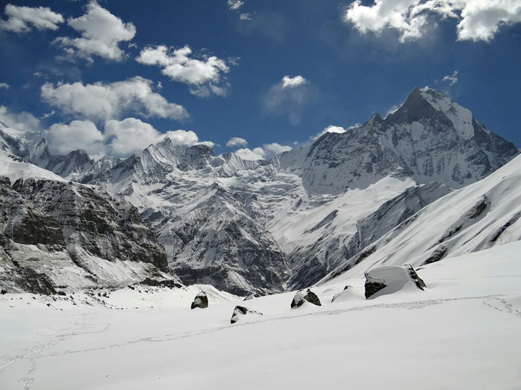 a snow covered mountain range under a partly cloudy sky