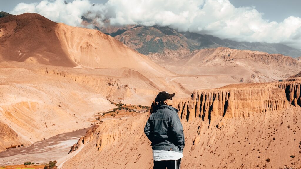 man in black jacket standing on brown rock formation during daytime