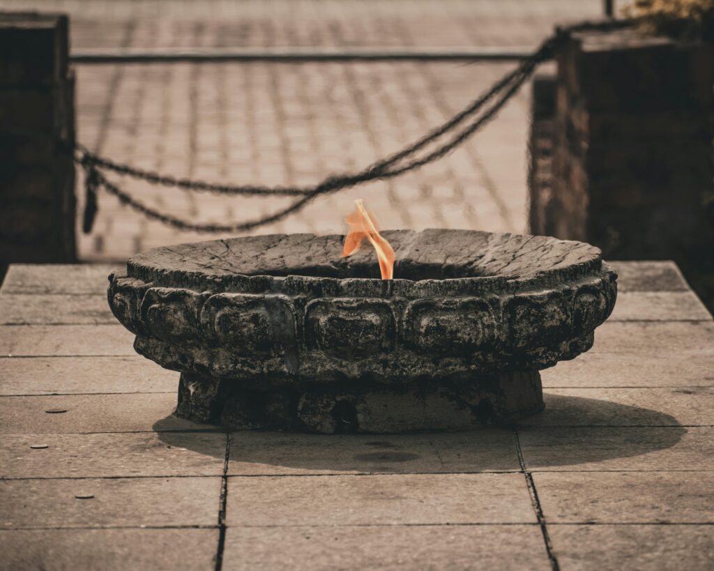 A sacred flame burns on a stone burner in Lumbini, capturing spiritual essence.
