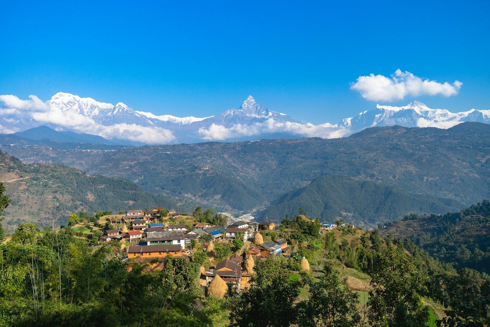 a small village on a hill with mountains in the background