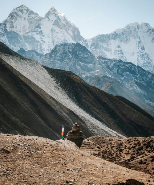 person in orange jacket standing on brown rocky mountain during daytime